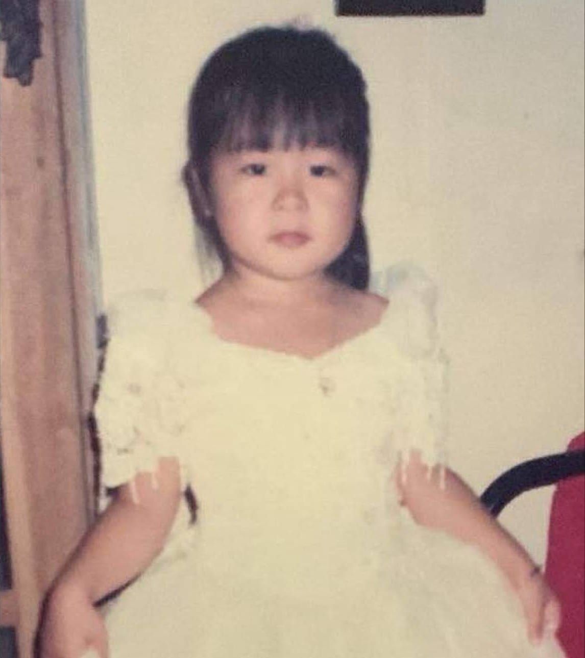 Then: Anna as a little girl with straight bangs, in a little gown with ruffled sleeves, in an old, faded print.